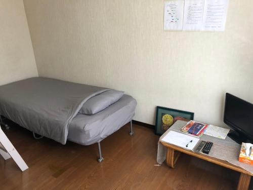 a small bedroom with a bed and a table at 竜ヶ崎駅そばのゲストハウスM&M in Ryūgasaki