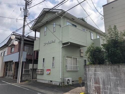 a green building on the side of a street at 竜ヶ崎駅そばのゲストハウスM&M in Ryūgasaki
