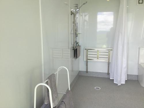 a white bathroom with a shower and a sink at Waihi Gold Alpacas 1 or 2 people in Waihi
