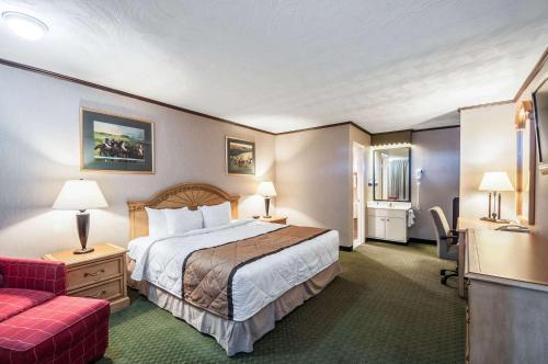 um quarto de hotel com uma cama e um sofá vermelho em Rodeway Inn and Suites - Charles Town,WV em Charles Town