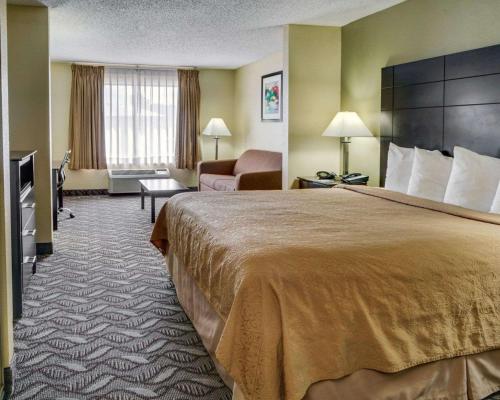 a hotel room with a large bed and a chair at Quality Suites Baton Rouge East - Denham Springs in Baton Rouge