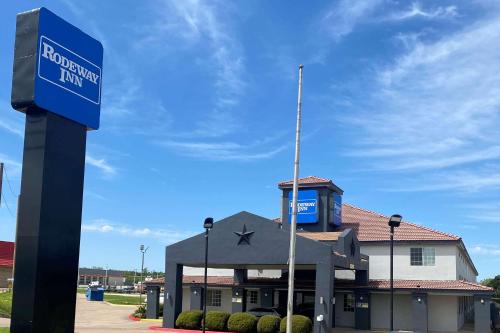 a building with a blue sign in front of it at Rodeway Inn in Stephenville