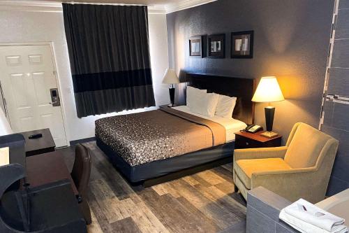 Pokój hotelowy z łóżkiem i krzesłem w obiekcie Rodeway Inn w mieście Stephenville