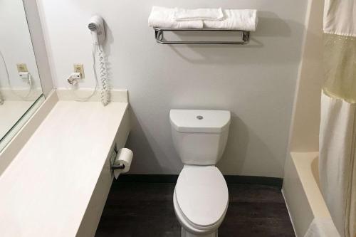 a bathroom with a toilet and a phone on the wall at Rodeway Inn in Stephenville