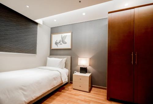 a bedroom with a white bed and a red closet at Oriens Hotel & Residences Myeongdong in Seoul