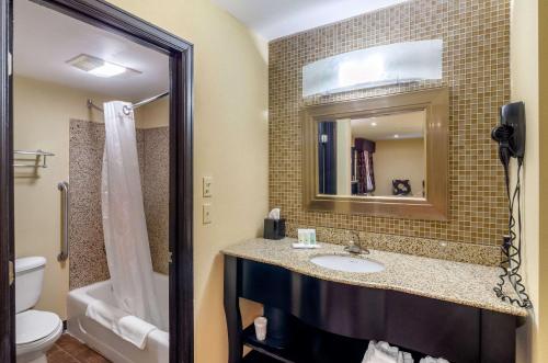 a bathroom with a sink and a toilet and a mirror at Quality Inn in Covington