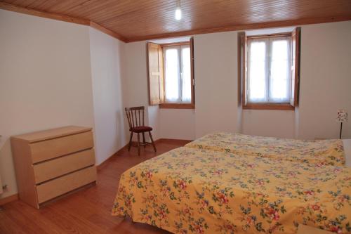 a bedroom with a bed and a dresser and two windows at Casa das Tias in Manteigas