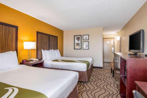 a hotel room with two beds and a flat screen tv at Quality Inn in Sweetwater