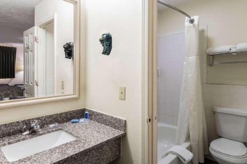 a bathroom with a sink and a toilet and a mirror at Rodeway Inn Cadiz in Cadiz