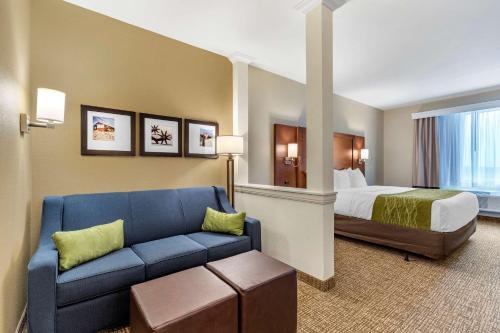 a hotel room with a bed and a blue couch at Comfort Suites San Antonio Ft Sam Houston-SAMMC Area in San Antonio