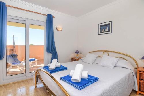 Un dormitorio con una cama con toallas azules. en Poolbeach V, en Moraira