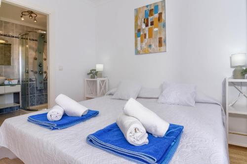 un letto bianco con asciugamani blu sopra di Poolbeach VI a Moraira
