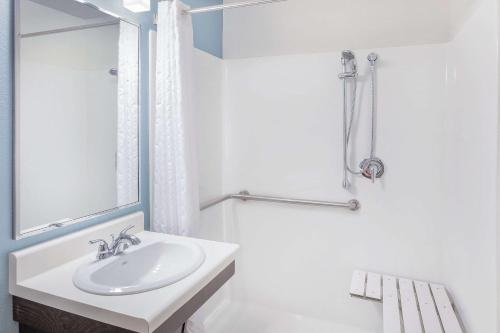 Baño blanco con lavabo y espejo en WoodSpring Suites Las Colinas - Northwest Dallas en Irving