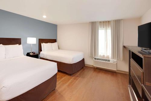 Habitación de hotel con 2 camas y TV de pantalla plana. en WoodSpring Suites Las Colinas - Northwest Dallas en Irving