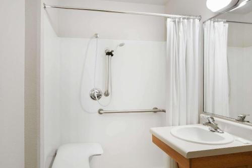 a white bathroom with a toilet and a sink at WoodSpring Suites Fort Worth Forest Hill in Forest Hill