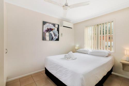 a bedroom with a white bed and a window at Discovery Parks - Coolwaters, Yeppoon in Kinka