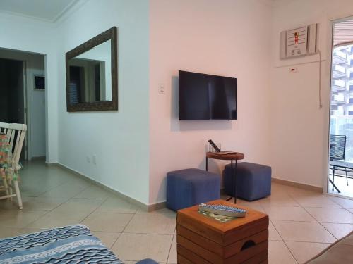 a living room with a tv on the wall and a table at Neto & Costa in Guarujá