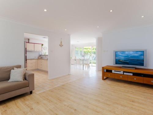 a living room with a couch and a flat screen tv at 8a Foreshore Drive Ducted Air and Boat Parking in Salamander Bay