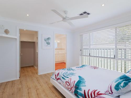 een witte slaapkamer met een bed en een raam bij 8a Foreshore Drive Ducted Air and Boat Parking in Salamander Bay