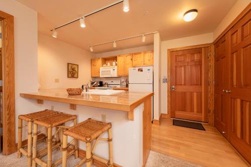 una cocina con armarios de madera y una barra con taburetes en Targhee Rentals 414 Teton Creek Resort Driggs ID, en Driggs