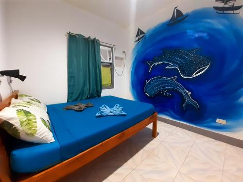 una habitación con una cama con una pintura de un delfín en Island Girl Bed and Breakfast, en Moalboal