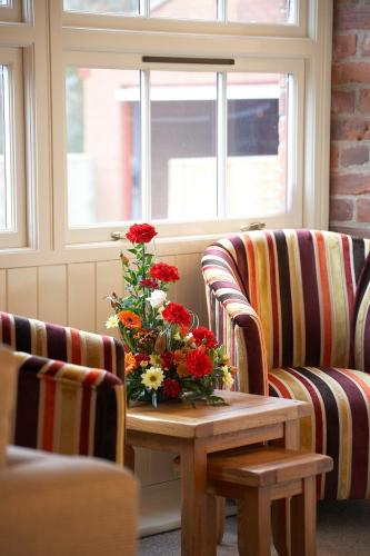 a room with two chairs and a table with a vase of flowers at Wold Escapes, Highfield Farm in Great Driffield