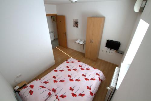 a small bedroom with a bed with a red blanket at Guest House Ivac Inn Zagreb Airport in Velika Gorica