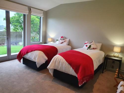 a bedroom with two beds with red and white blankets at Mangawhai Bay B&B in Omokoroa