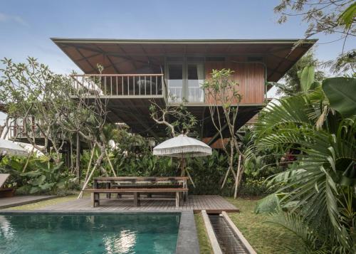 a house with a swimming pool and a bench and a house at Grün Canggu Garden in Canggu