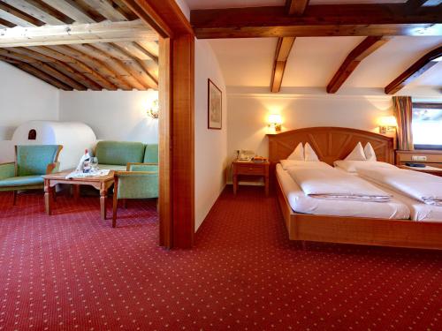 um quarto com uma cama, um sofá e uma cadeira em Hotel Arlberg em Sankt Anton am Arlberg