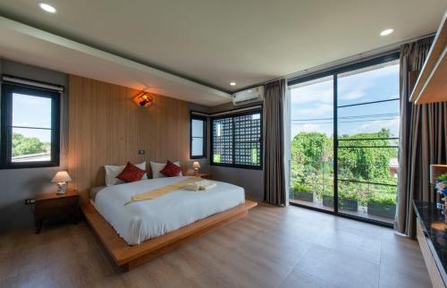 ein Schlafzimmer mit einem großen Bett und großen Fenstern in der Unterkunft Areya Villa in Chiang Mai