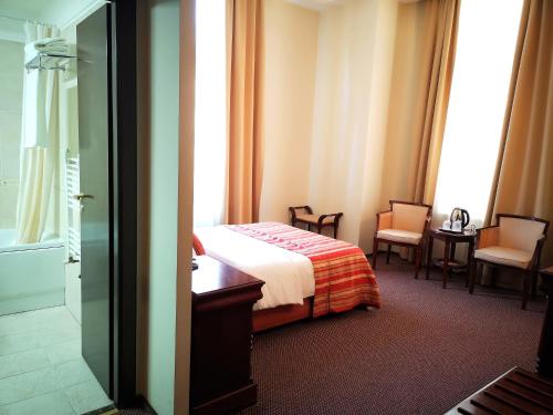 a hotel room with a bed and two chairs at Atrium Hotel Ateneu City Center in Bucharest
