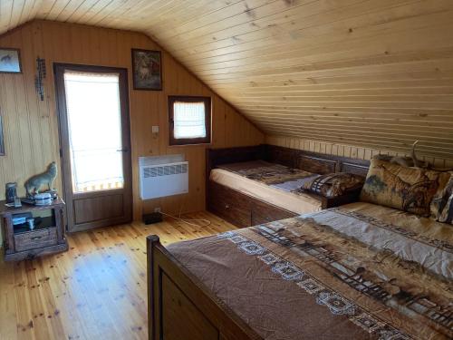 a bedroom with two beds in a wooden cabin at Ранчо Бандера in Tsŭrvenyano