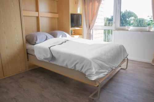 Schlafzimmer mit einem Bett mit weißer Bettwäsche und einem Fenster in der Unterkunft günstige Sankt Peter-Ording Ferienwohnung in Sankt Peter-Ording