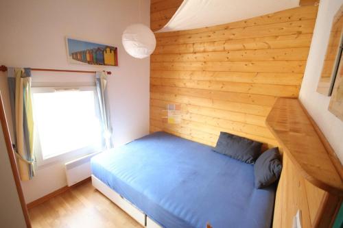 1 dormitorio con cama azul y pared de madera en Belle villa plein sud, 4-6 couchages, en résidence avec piscine commune, Wifi fibre optique, 400m de la mer à PORTIRAGNES PLAGE LROND5, en Portiragnes