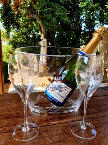 une bouteille de vin et deux verres à vin sur une table dans l'établissement Gîte Le Relais Coq'Lys, à Mareuil-sur-Ay