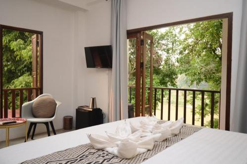 een slaapkamer met een bed en uitzicht op een balkon bij Moonlight Champa Riverview in Luang Prabang