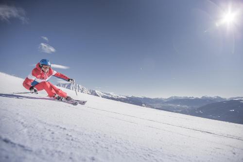 a man is skiing down a snow covered slope at Panoramahotel Huberhof in Maranza
