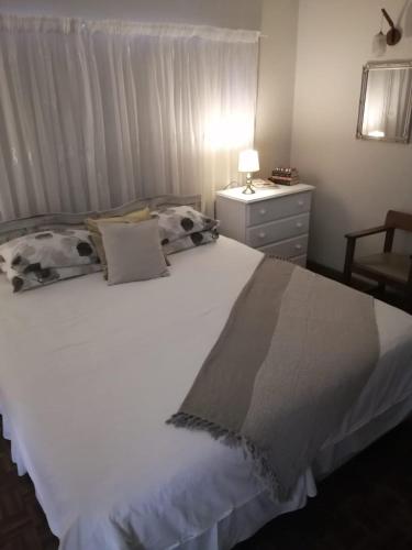 a bedroom with a white bed with a dresser and a lamp at 36 Mount Road Guesthouse and Self Catering in Port Elizabeth