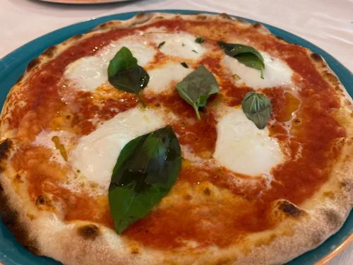 a pizza with green leaves on a blue plate at Impero Hotel Beauty & Spa - Bike Hotel in Cantello