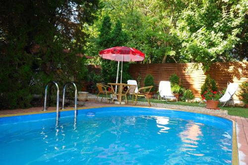 a swimming pool with a red umbrella and a table and chairs at Papillon Apartment in Budapest
