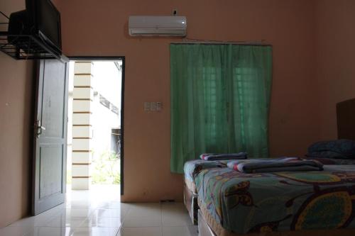 um quarto com 2 camas e uma cortina verde em Penginapan Transit Tomato em Tanjungmorawa