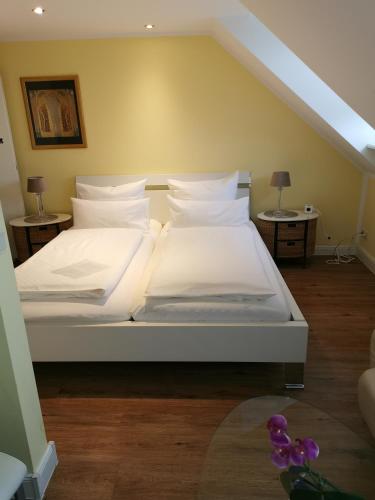 a bed with white sheets and pillows in a room at Stoevchen Café Hotel in Papenburg