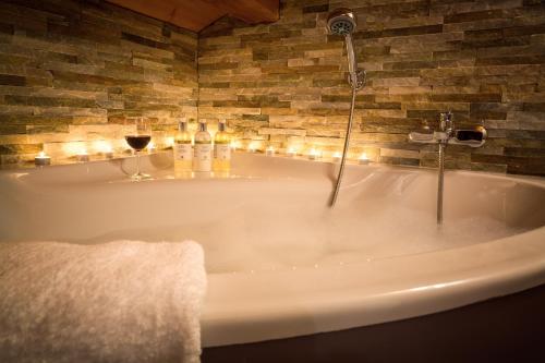a bath tub with candles and a glass of wine at Riverwood Lodge in Montriond