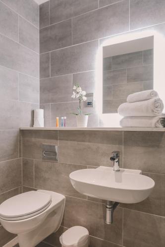 a bathroom with a sink and a toilet and a mirror at Park Lane Aparthotel by Urban Space in Cardiff