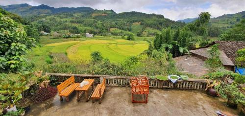 a group of tables and chairs on a balcony with a field at La Beauté Bắc Hà in Bắc Hà