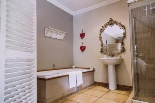 a bathroom with a tub and a sink and a mirror at Villiera Guesthouse in Douglas