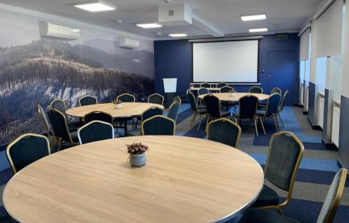 a conference room with tables and chairs and a screen at Hotel *** NAT Ustroń in Ustroń