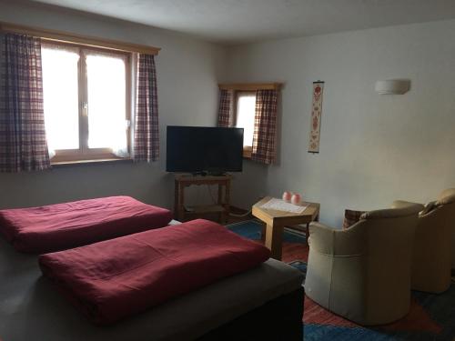 a living room with two ottomans and a television at Chesa Viletta in La Punt-Chamues-ch