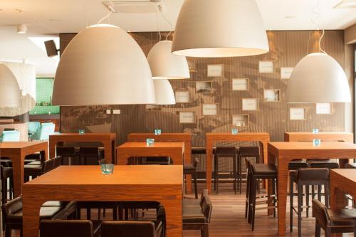 un restaurante con mesas, sillas y luces en Motel One Frankfurt Messe en Frankfurt